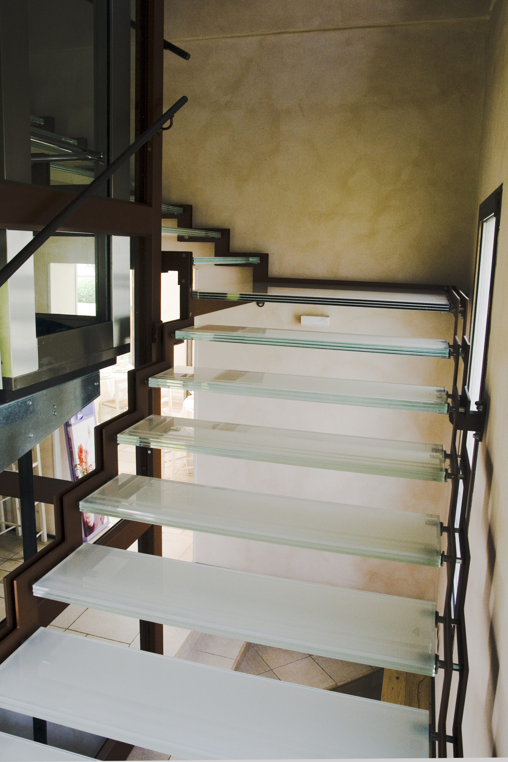 Scala con pavimentazione in vetro e struttura in acciaio in un edificio storico