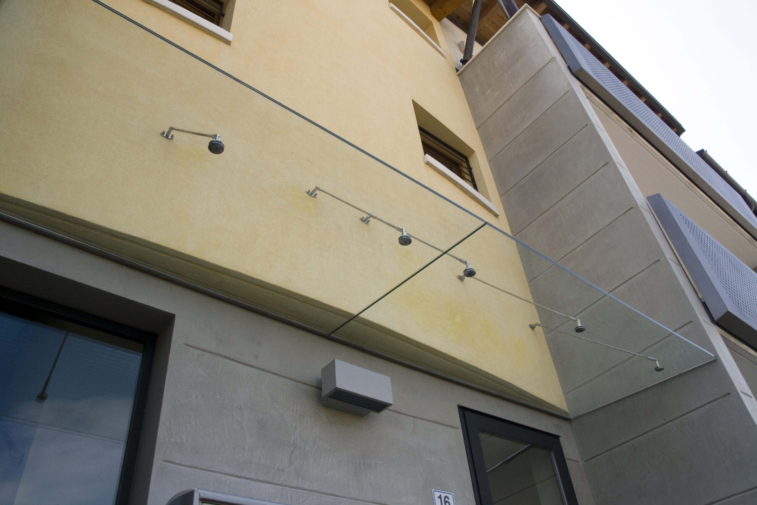 Soluzione architettonica di pensilina in vetro per un ingresso aziendale nel Veneto.