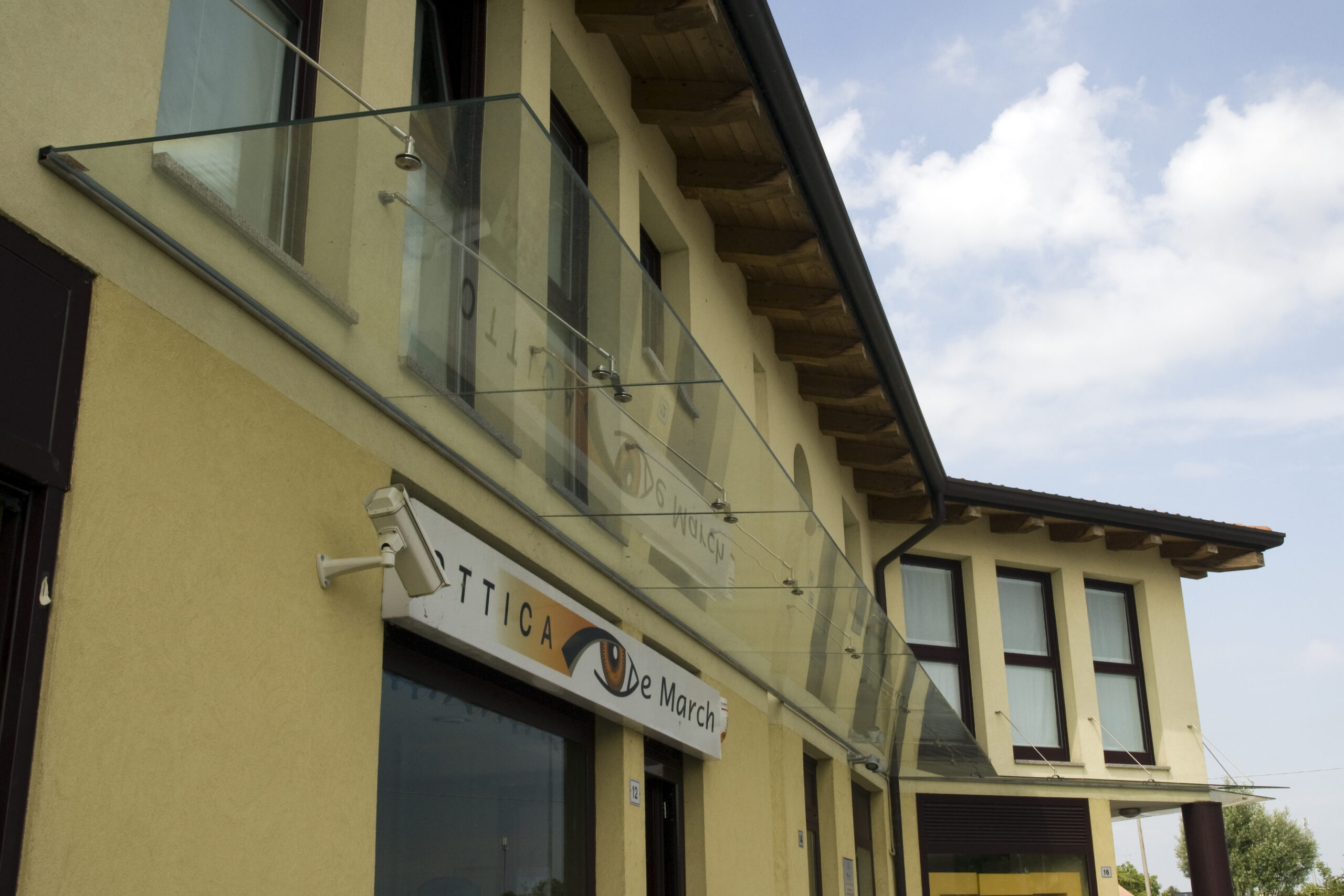 Pensilina in vetro moderna sopra l'ingresso di un edificio commerciale a Treviso.