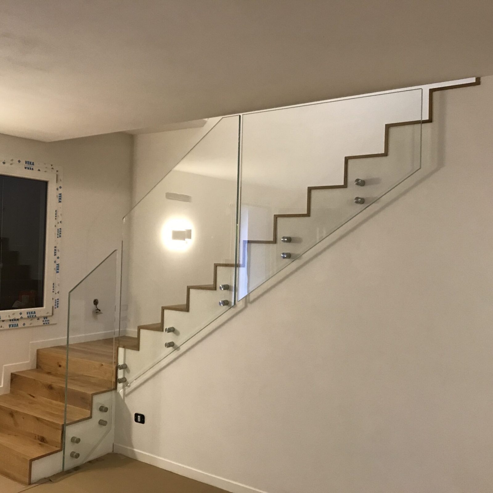 Dettaglio di un parapetto in vetro per scala interna, design minimalista, Veneto.