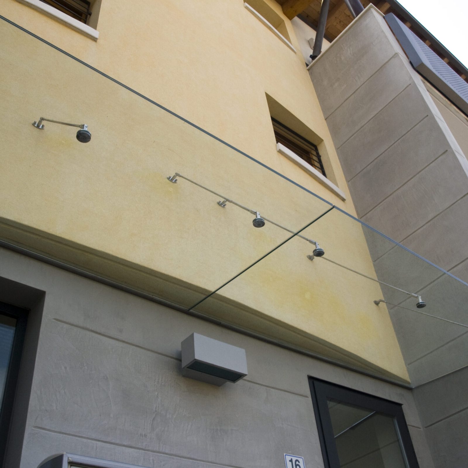 Soluzione architettonica di pensilina in vetro per un ingresso aziendale nel Veneto.