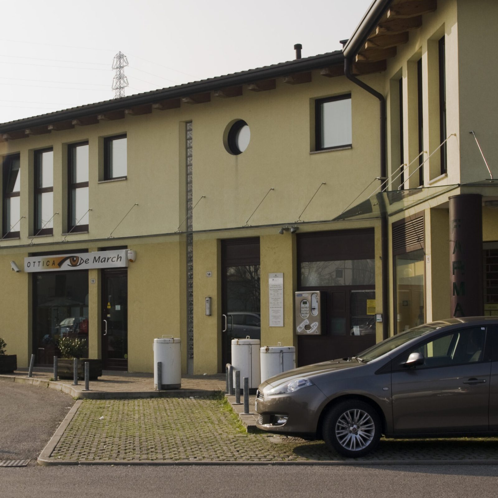 Pensilina in vetro trasparente che protegge un patio esterno, design minimalista a Treviso.