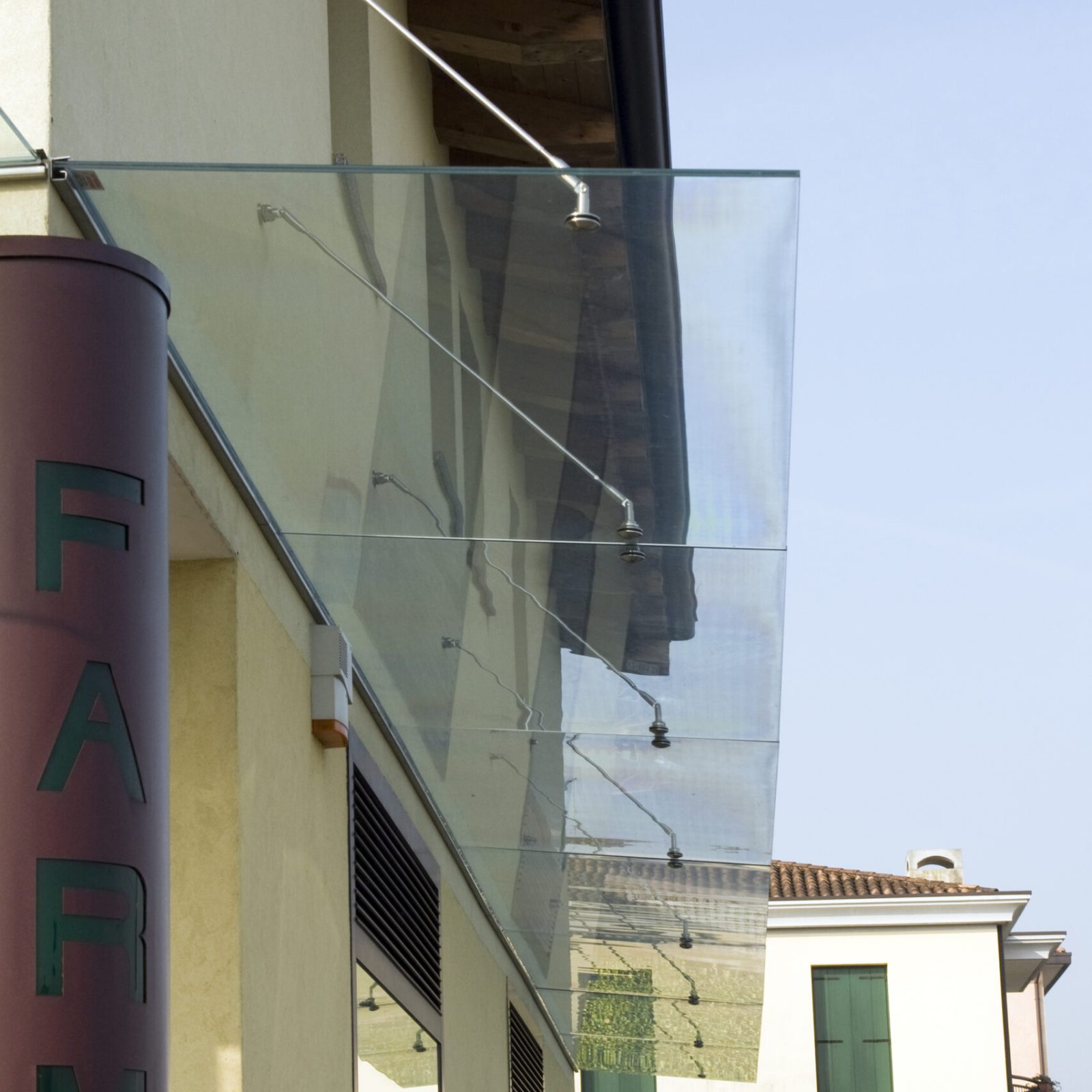 Pensilina in vetro con tiranti in acciaio fuori da un edificio commerciale